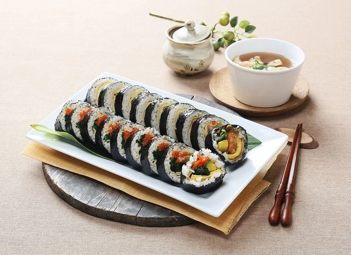 흰 접시에 가지런히 담긴 김밥과 유부 국물, 나무 젓가락이 놓인 상차림