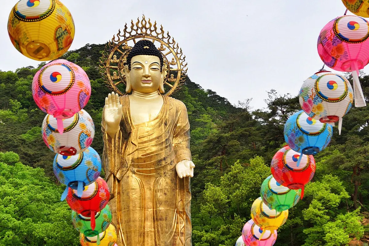 속리산 법주사의 금동미륵대불. 황금빛 대불 좌우로 연등이 걸려 있고 뒤로 소나무가 우거진 산자락이 펼쳐져 있다