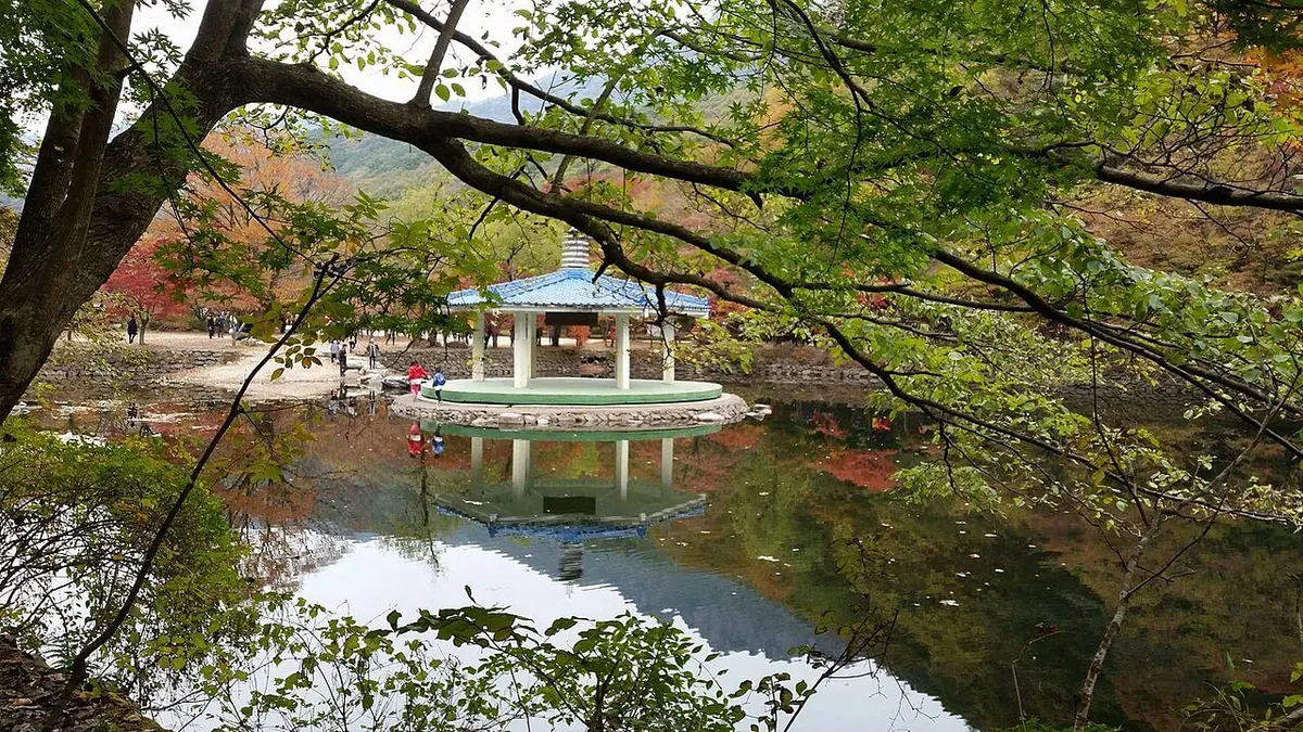 내장산 우화정 연못 풍경. 물 위에 정자가 비치고 주변 나무들이 초록에서 붉은색으로 물들기 시작한 이른 가을 모습이다