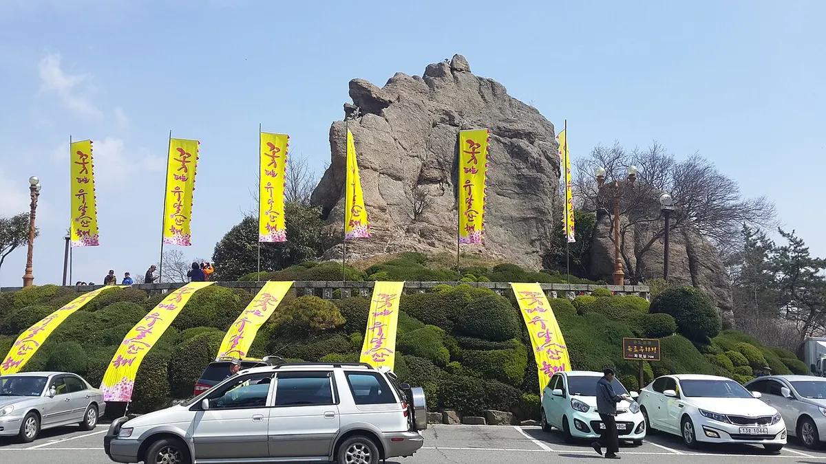 맑은 날 목포 유달산 노적봉의 큰 바위 봉우리와 그 앞에 걸린 노란 축제 깃발들