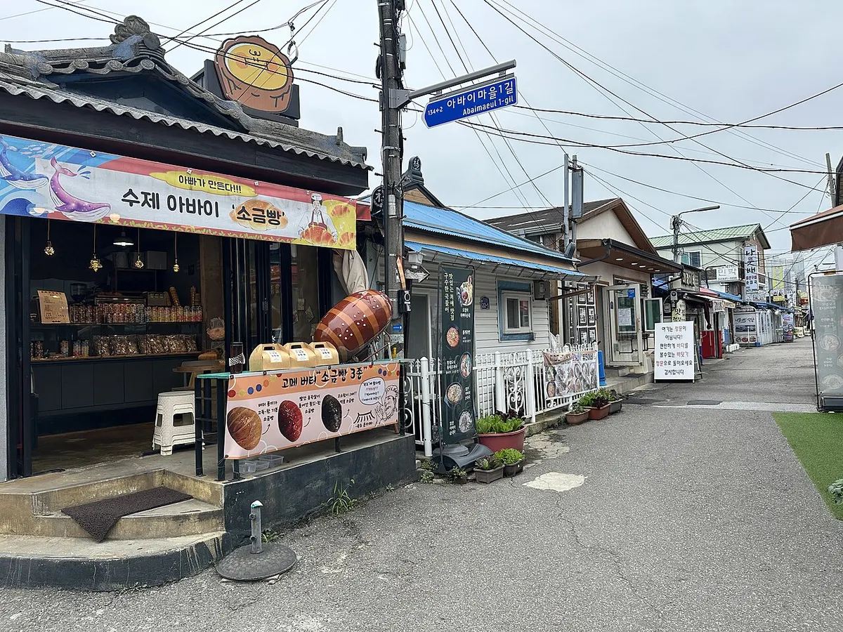 속초 아바이마을 골목길, 아바이마을1길 표지판과 순대·소금빵 등을 파는 가게들이 늘어선 거리 풍경